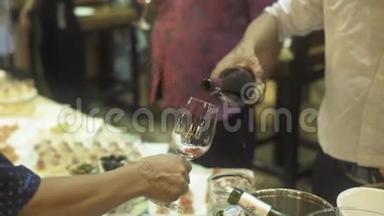 服务员在宴会上把红酒倒入玻璃杯中. 在宴会上把红酒倒入酒杯里的人